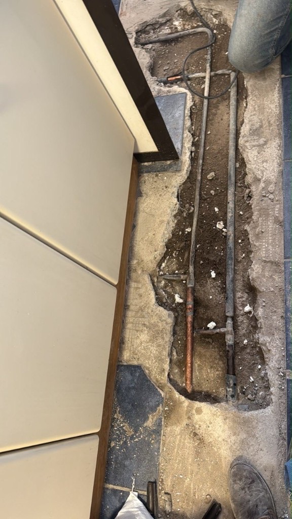 Piso abierto con tuberías de cobre antes de la reparación